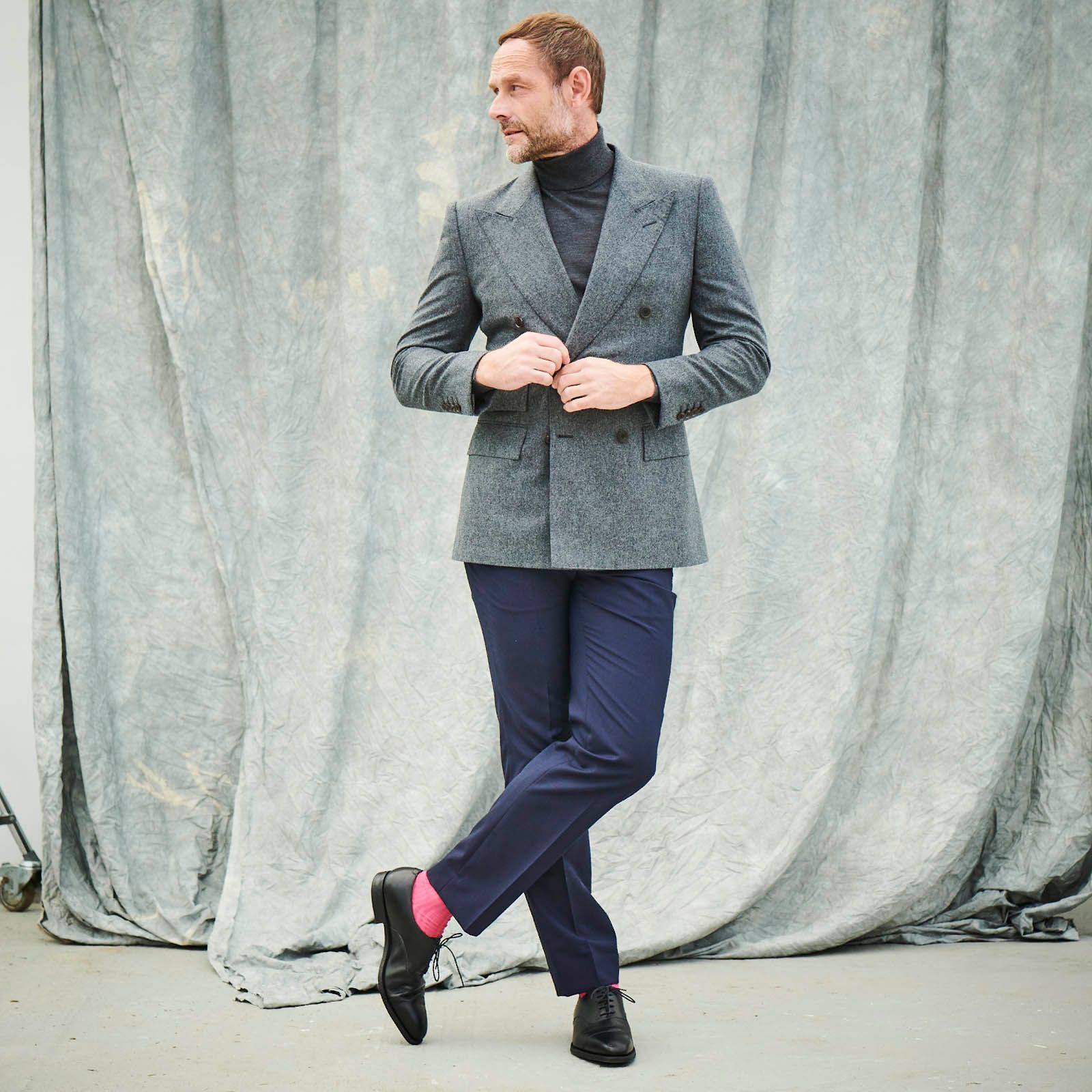 A man in a suit wearing pink socks with smart black shoes