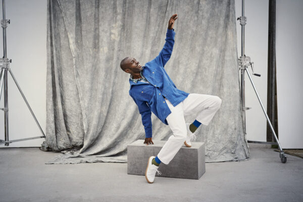 A model poses joyfully wearing denim and chinos with green and blue socks from London Sock Company