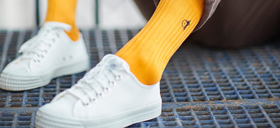 Close up of men's yellow socks from London Sock Company and white trainers