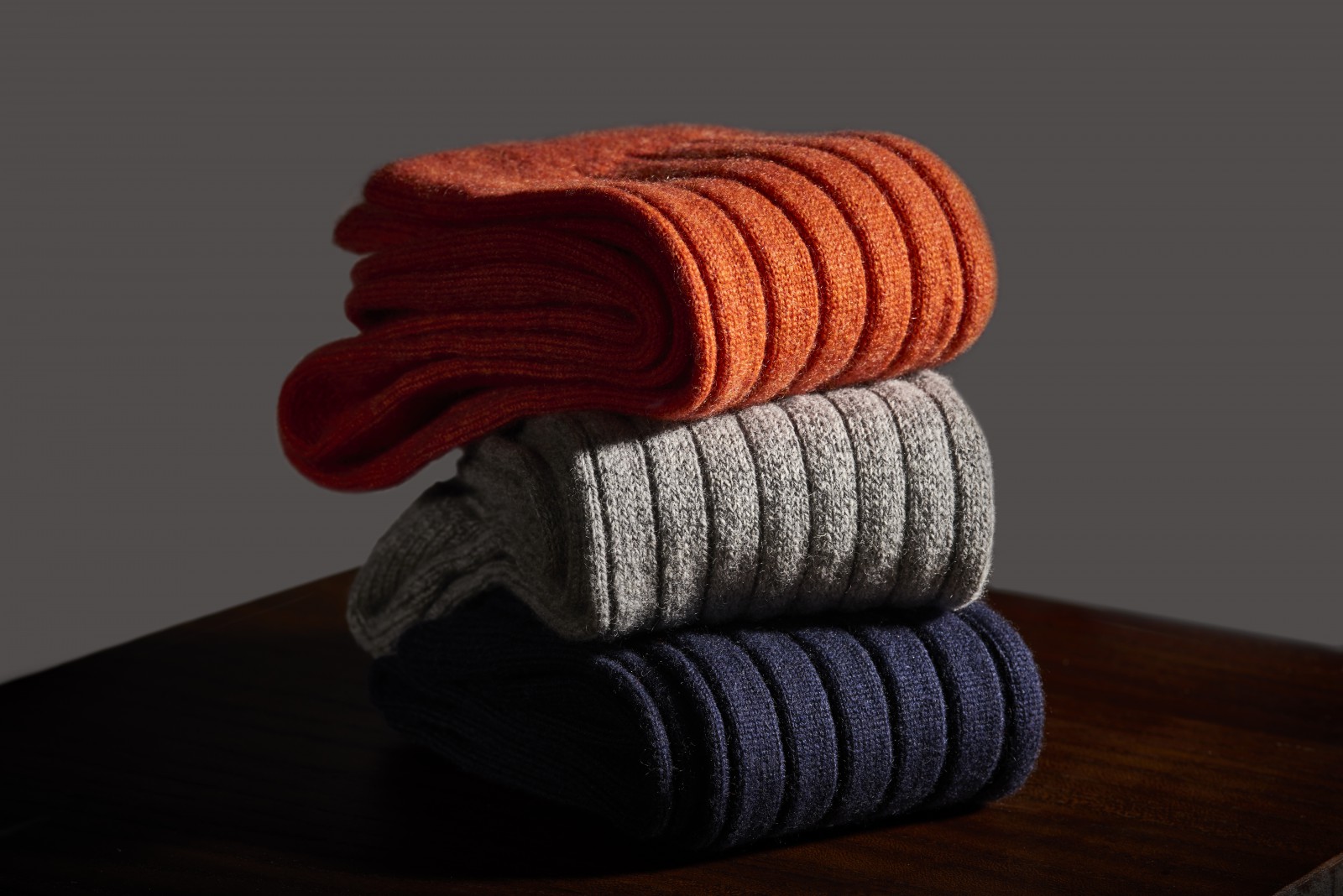 Three socks piled on top of each other, in orange, grey and blue