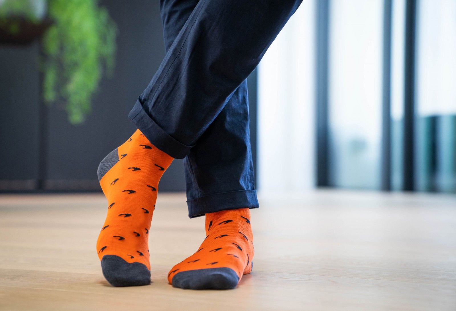 Two male feet with orange socks that have mclaren speedmark logo on. 