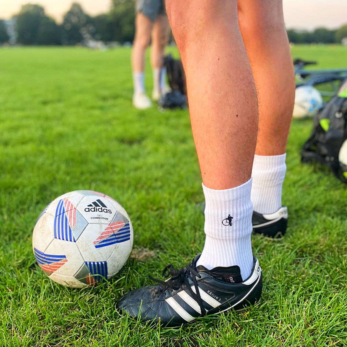 A person wearing white sports socks by London Sock Company with a football at a five-a-side match