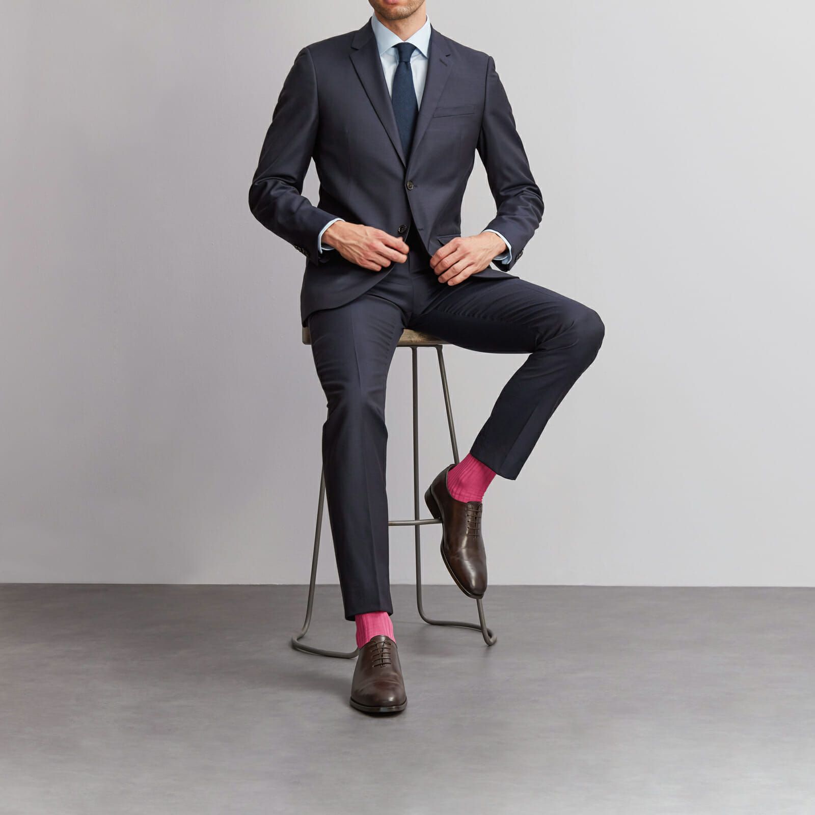Man in dark suit wearing pink socks