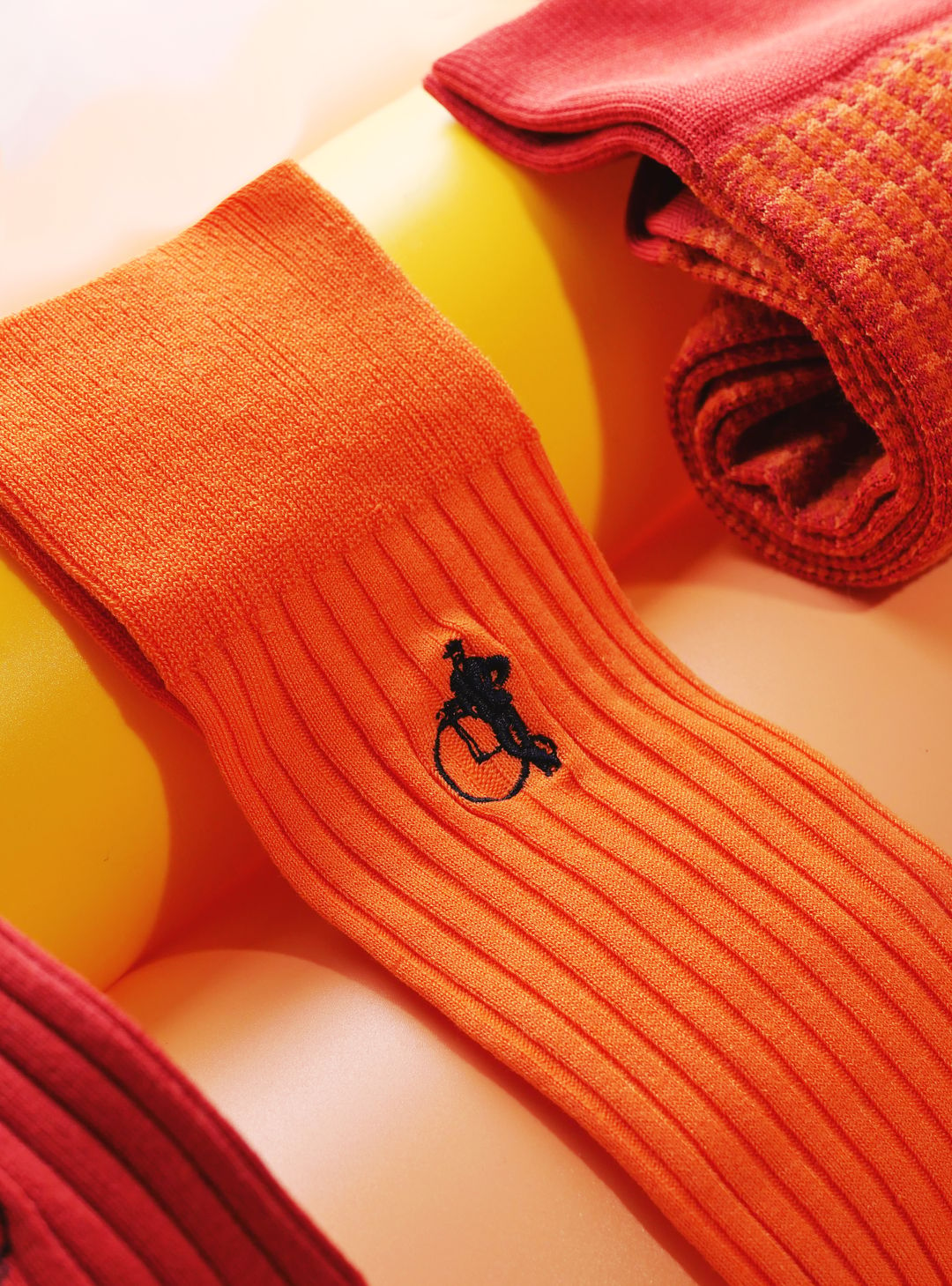 Three pairs of orange socks on a yellow background.