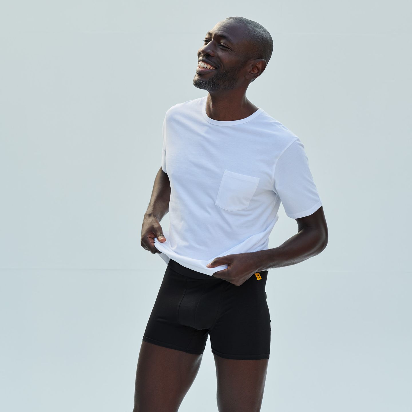 A person standing up wearing a white t shirt and black boxers