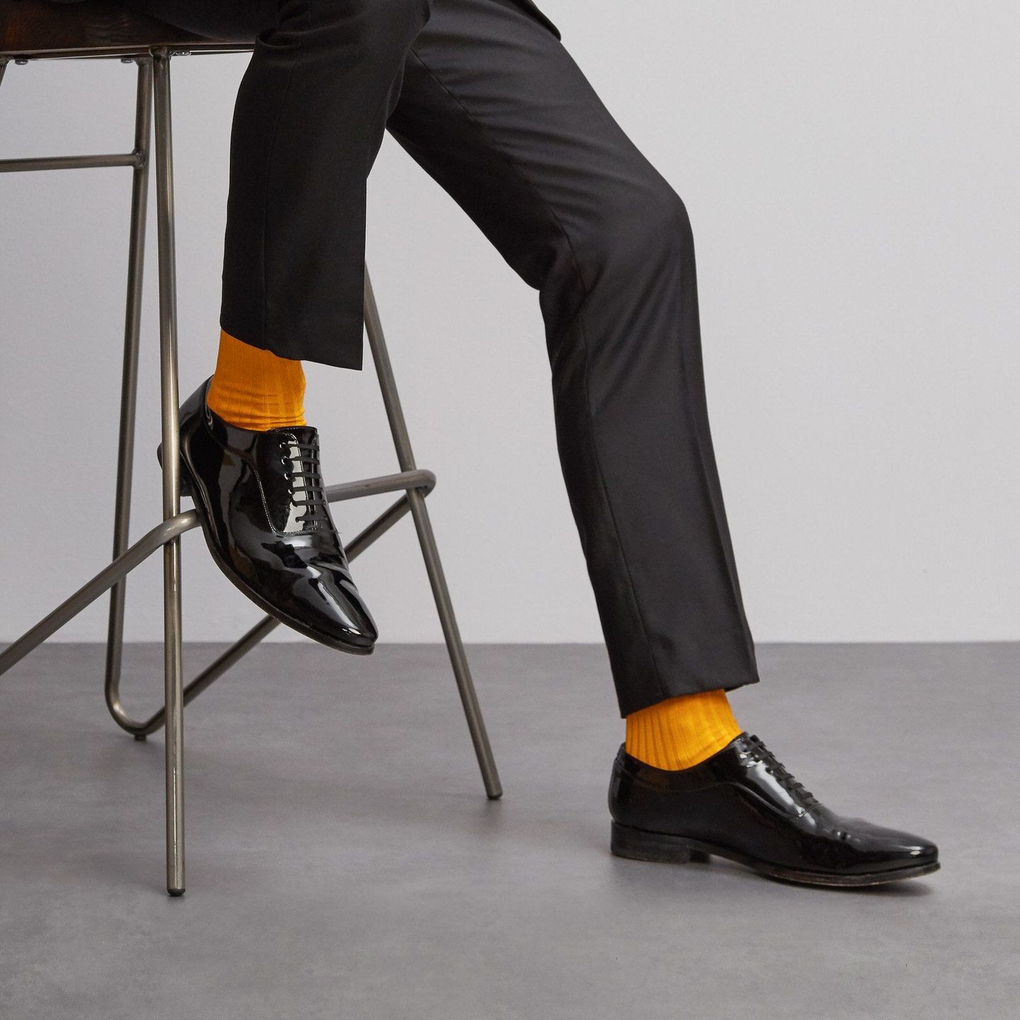 Close up of a sitting man in saffron socks, black shoes and trousers