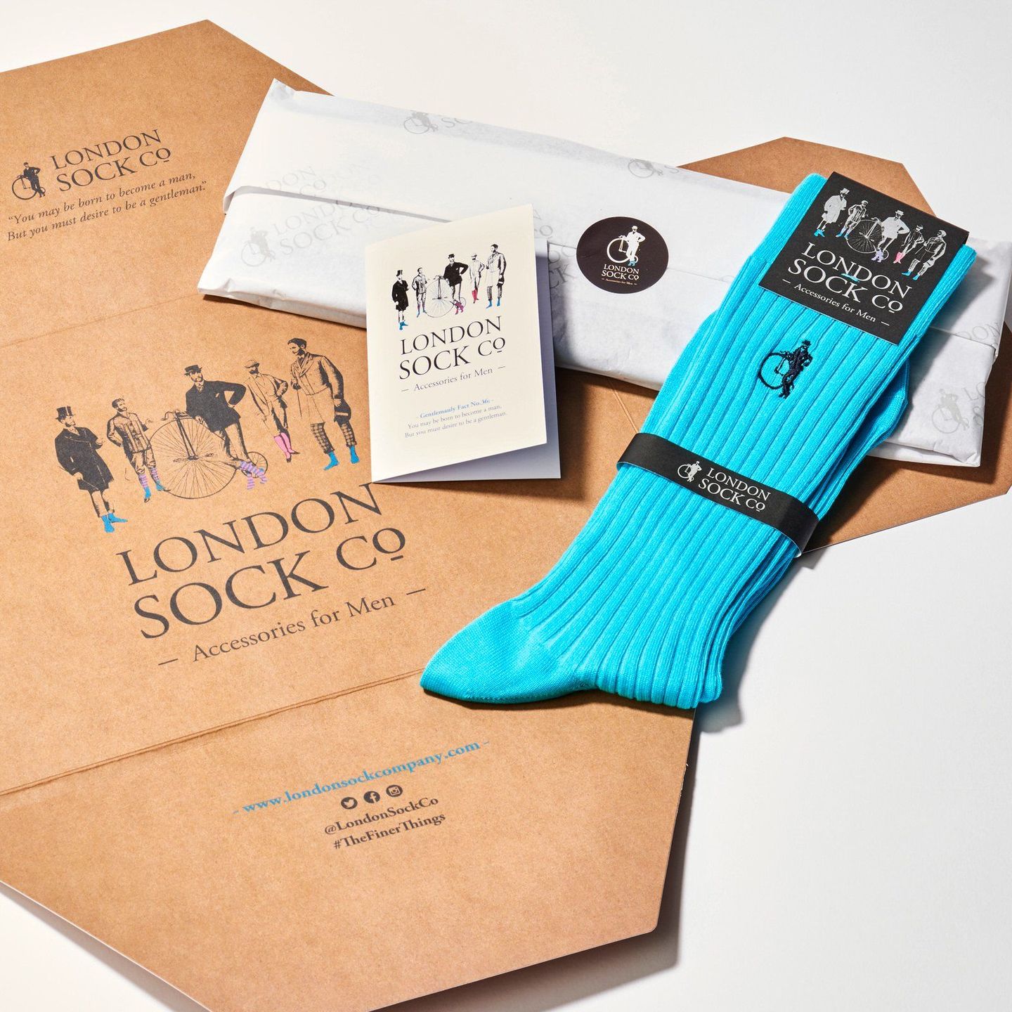 Starter pack with turquoise socks, wrapped socks and a card on top of brown branded packaging