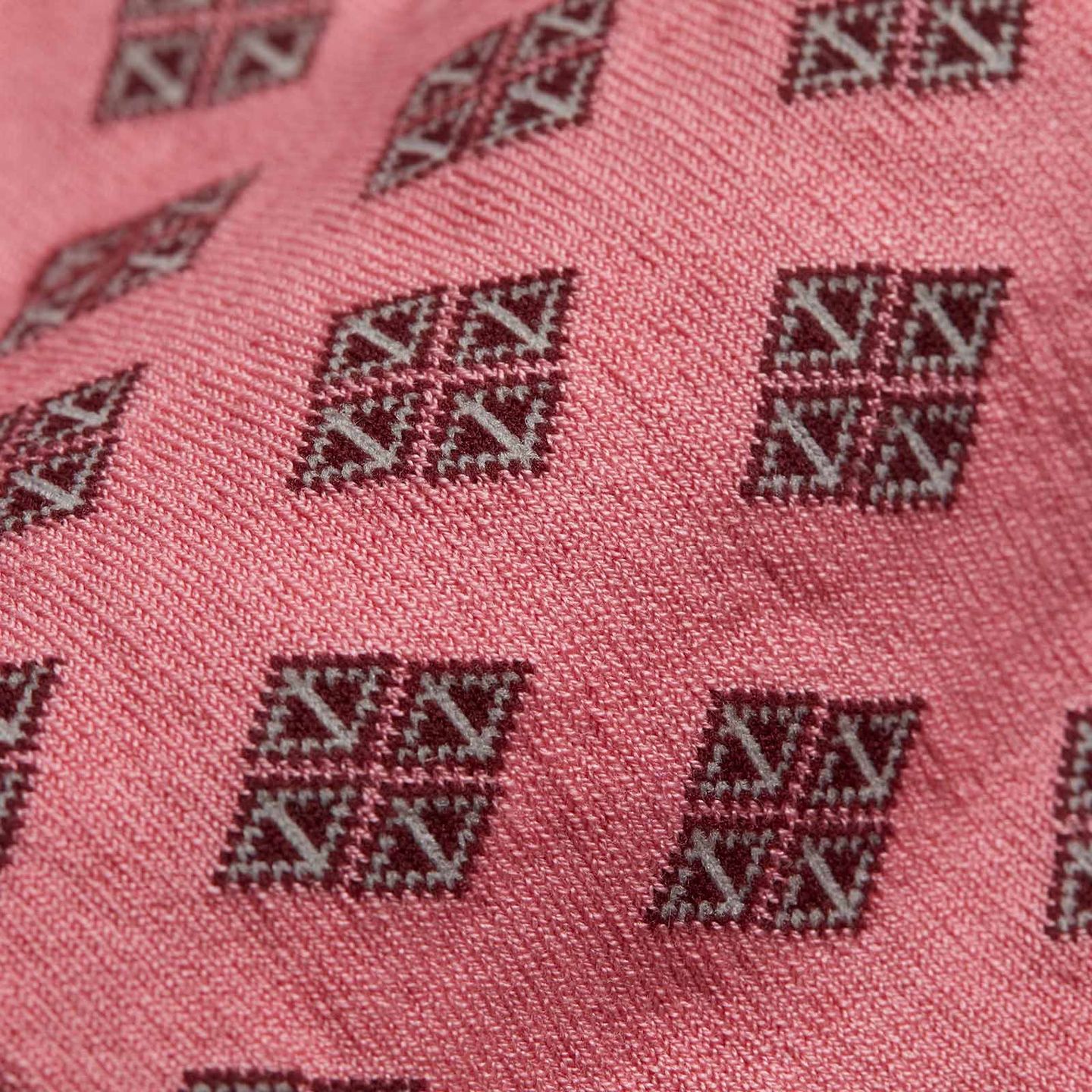 A close up of a pink sock with squared patterns