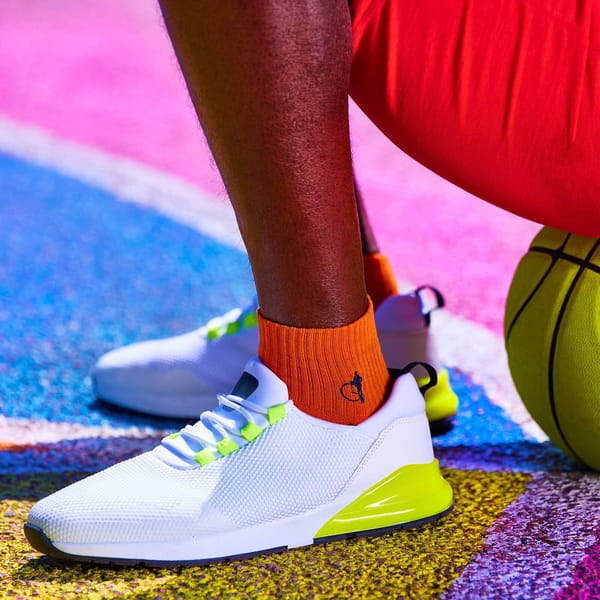 A close up of a person wearing orange socks with white trainers