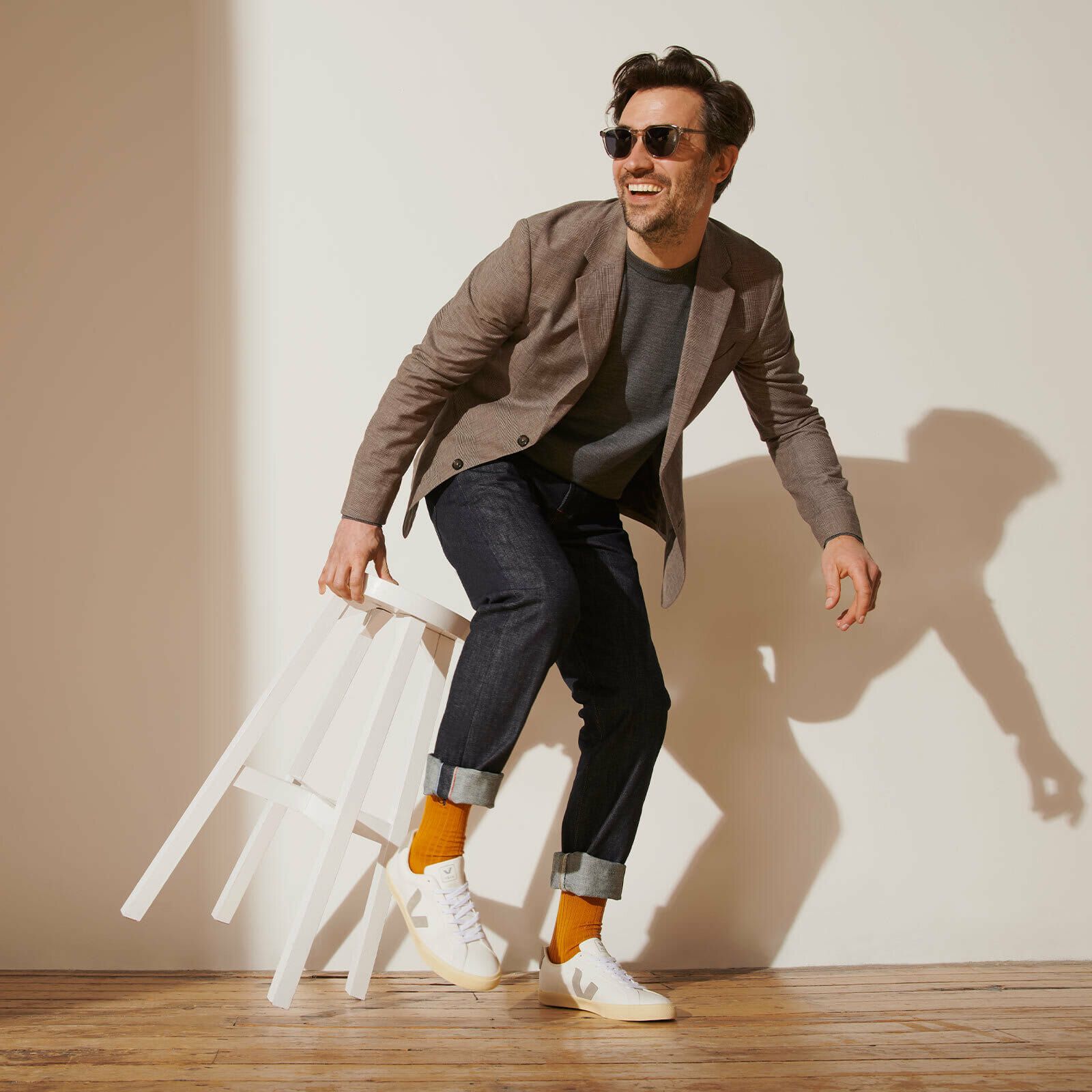 Man preparing to sit on stool he's hold wearing mango orange socks