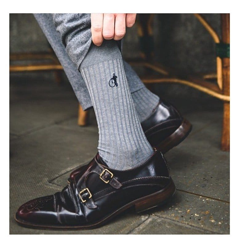 Close up of a trouser leg being pulled up to show a pair of grey sartorial socks