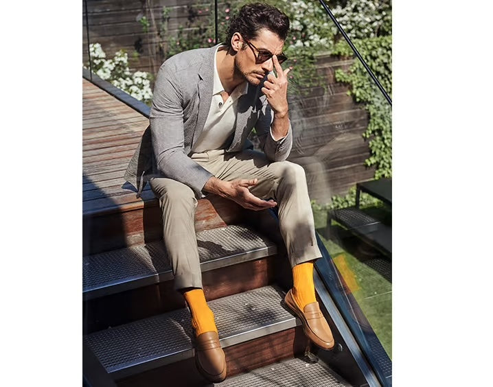 Person sitting down wearing orange socks with smart brown shoes