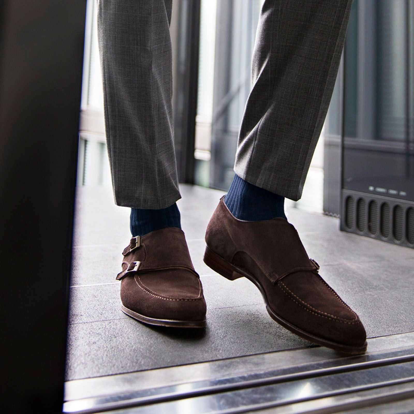 A close up of a person wearing dark blue socks with smart brown shoes