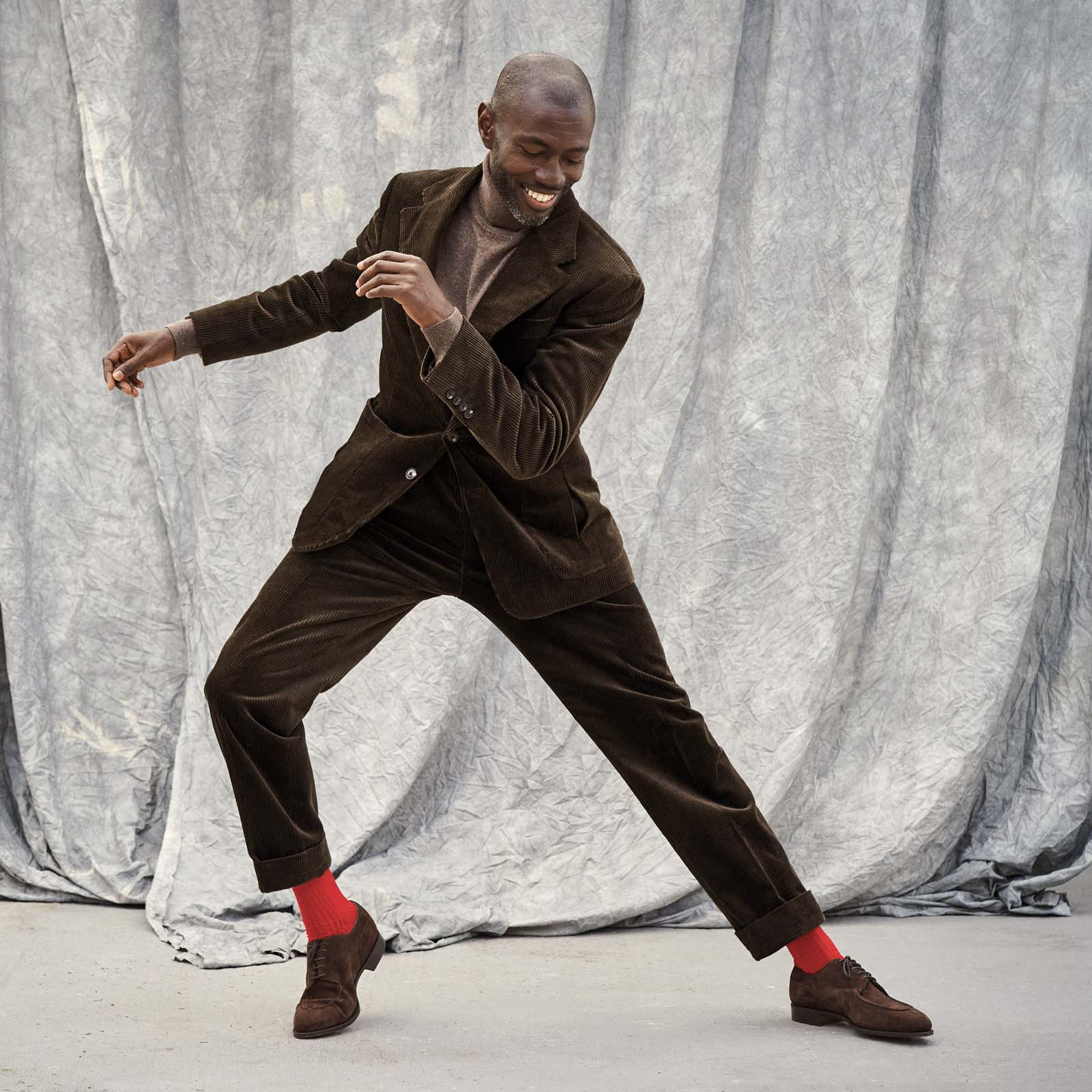 Man dancing by himself in a brown cord suit and routemaster red socks