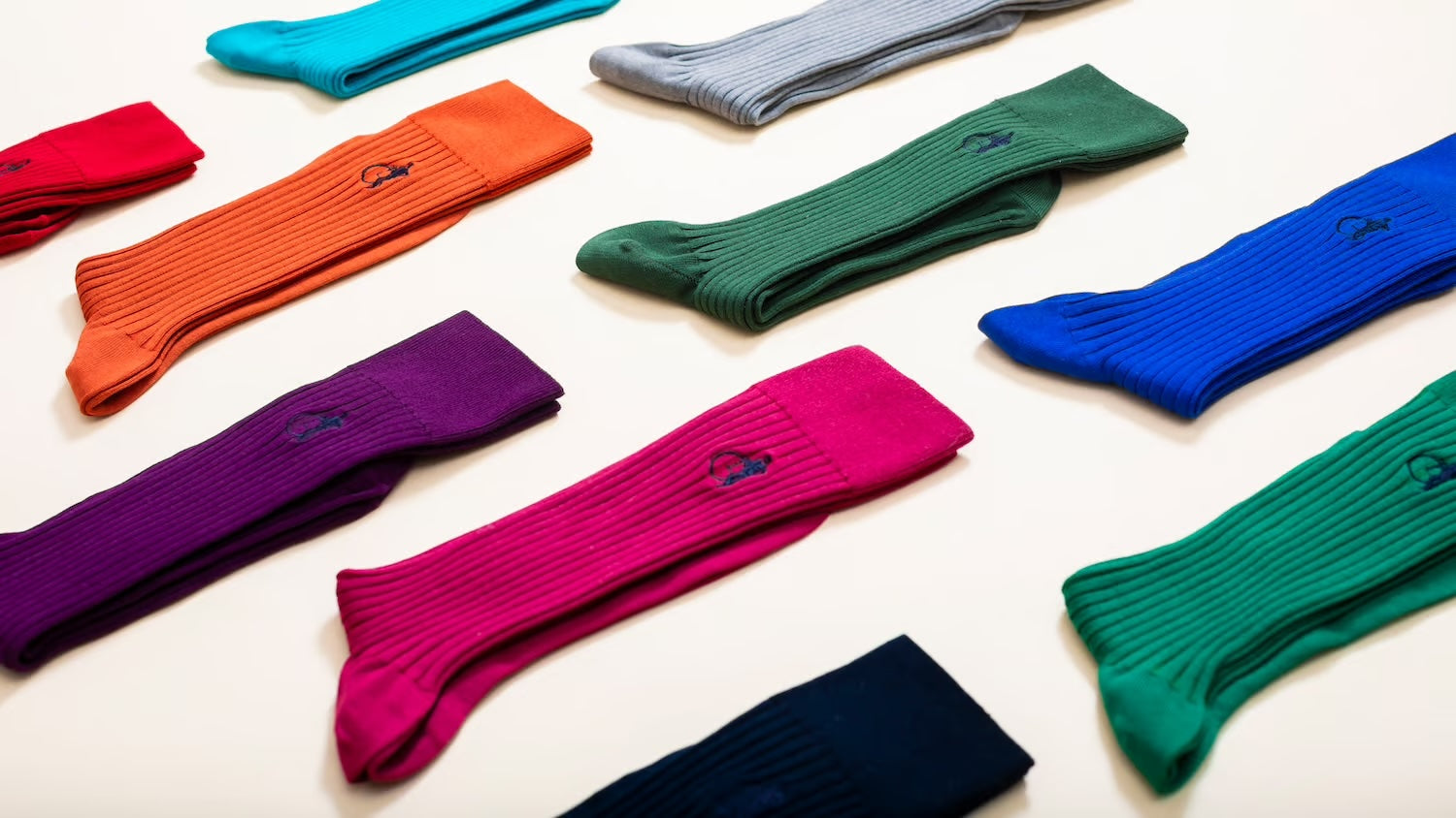 Sartorial socks laid out on a flat surface, featuring a cobalt blue, purple, pink and ruby red