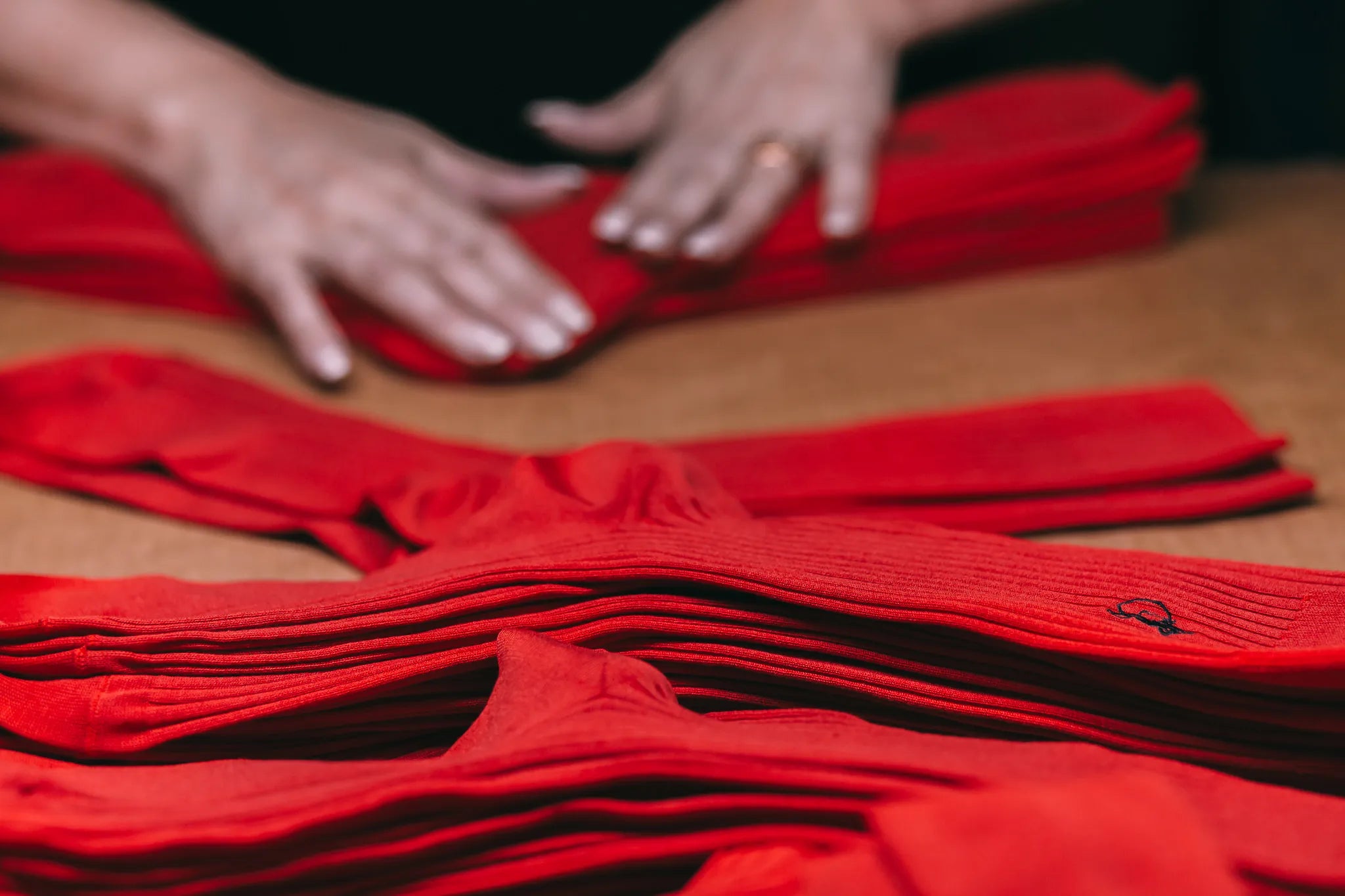 A close up of a person folding numerous red pairs of socks