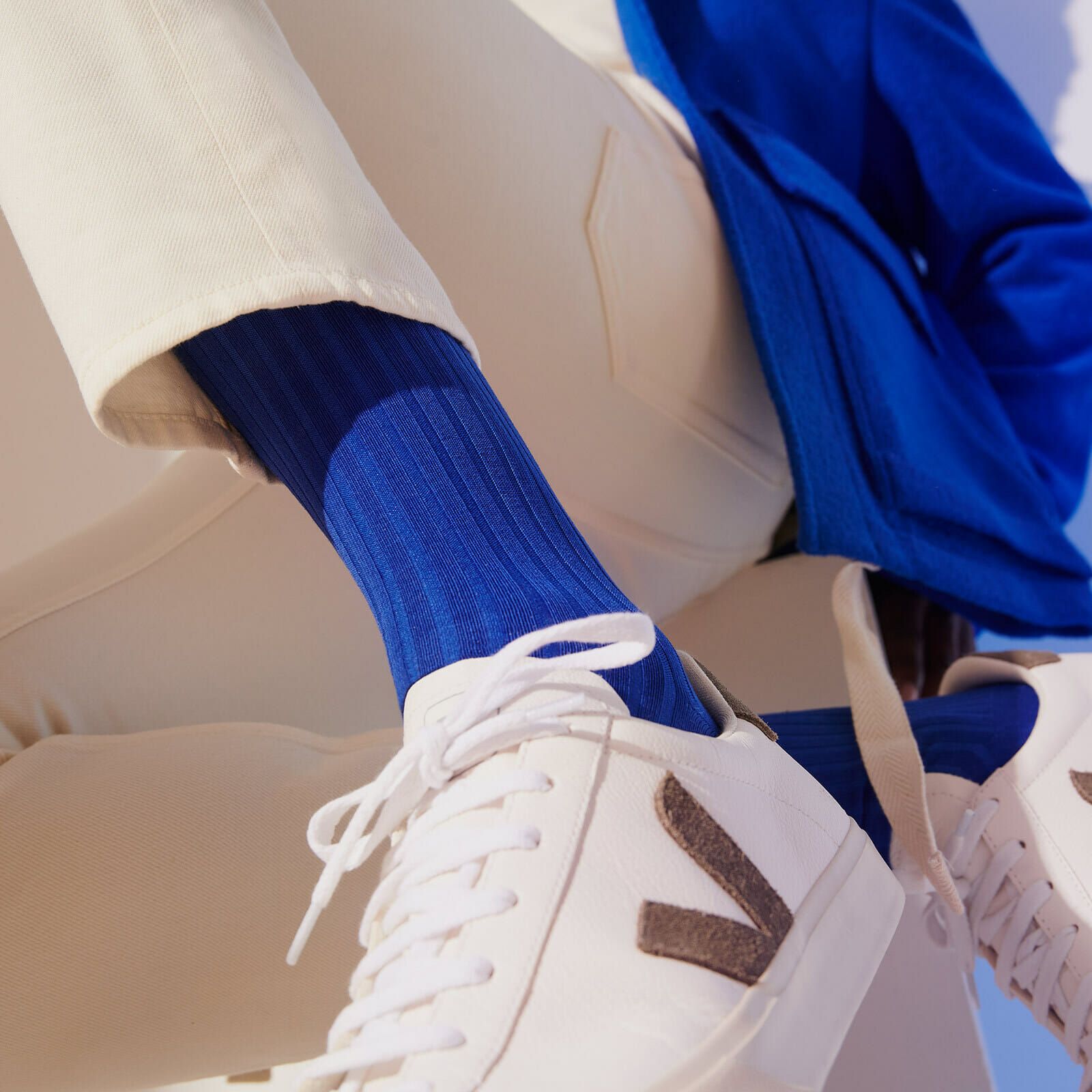 Close up of a man sitting wearing midnight blue socks and white trainers